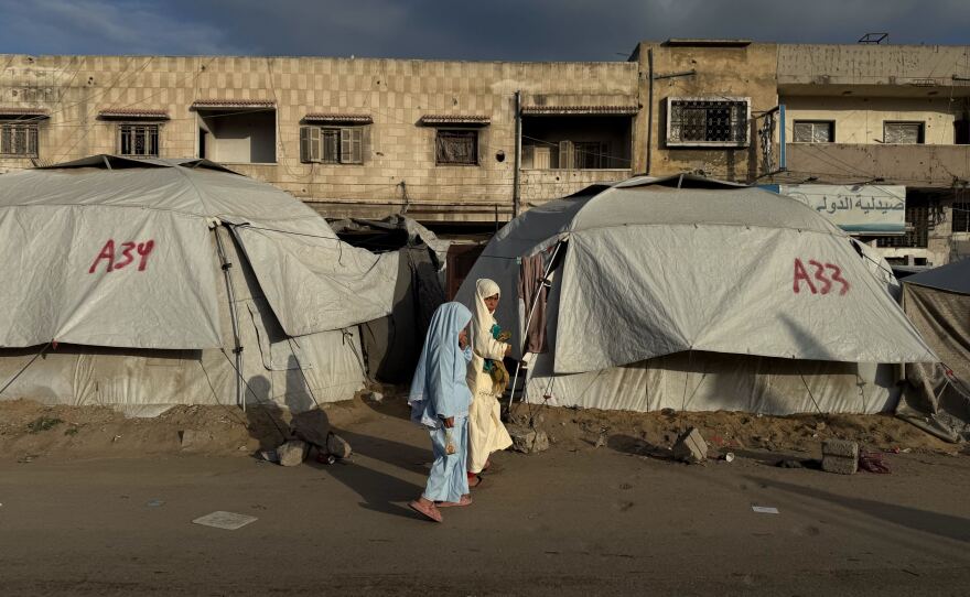 Girls walk past tents in Gaza City on Friday. For two years of war, Gaza's streets shook with the sound of deadly Israeli airstrikes