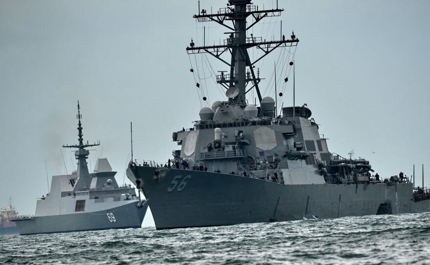 The USS John S. McCain sails toward a naval base in Singapore in August, the massive dent in its side visible on the right side of the frame. The destroyer had collided with a tanker just hours before — the second such deadly collision involving a U.S. Navy warship in several months.