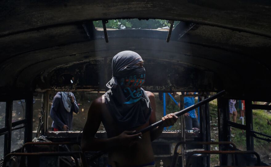 A protester looks around the interior of a burned out bus, which was set alight in Tipitapa during the daylong national strike Thursday.