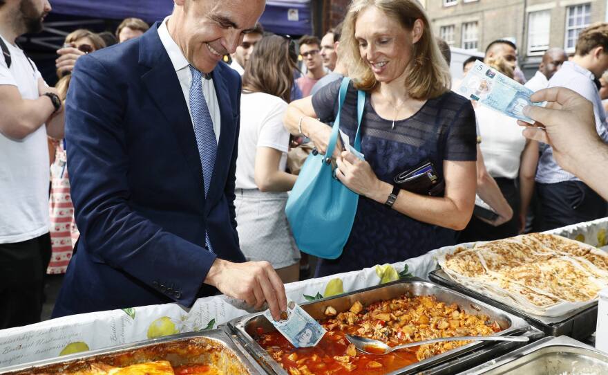 The governor of the Bank of England, Mark Carney, tests the polymer 5-pound note as he buys lunch in London on Tuesday.