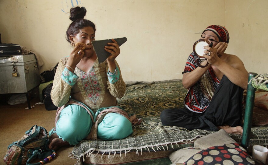 Shazia (left) and Nargis apply makeup before begging at a intersection in Lahore.