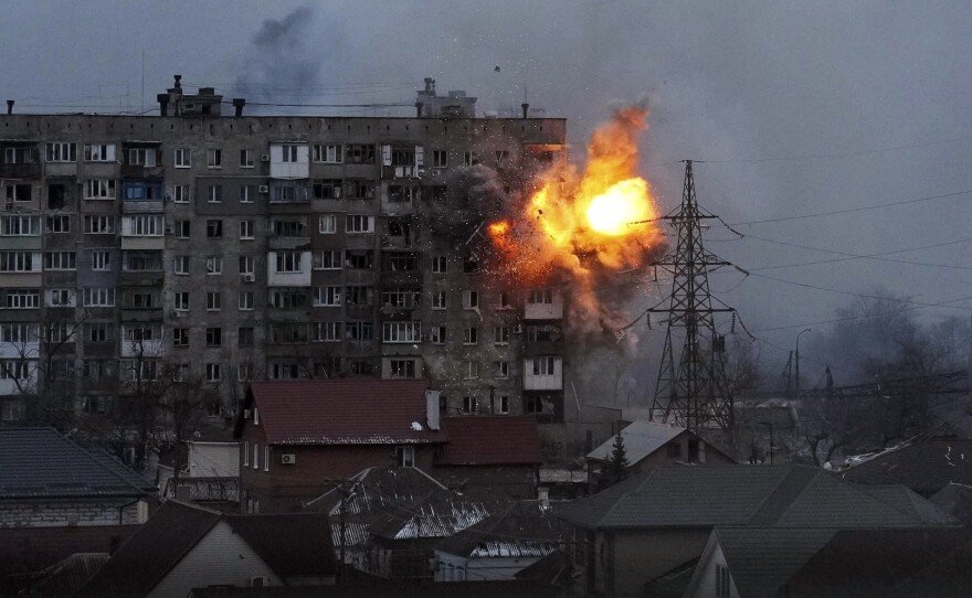 An explosion is seen in an apartment building after a Russian army tank fires in Mariupol, Ukraine, on Friday.