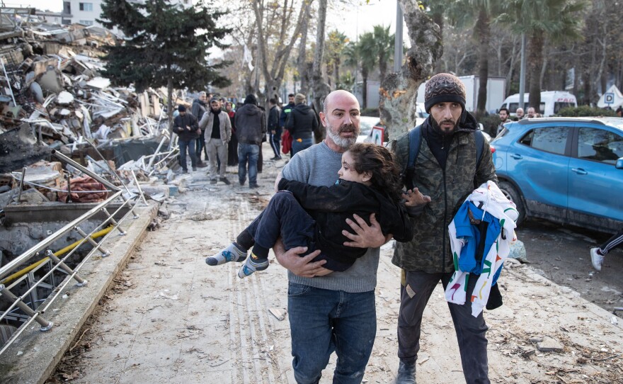 A man carries a child from a collapsed building in Hatay, Turkey. A 7.8-magnitude earthquake hit near Gaziantep, Turkey, in the early hours of Monday, followed by another 7.5-magnitude tremor just after midday.