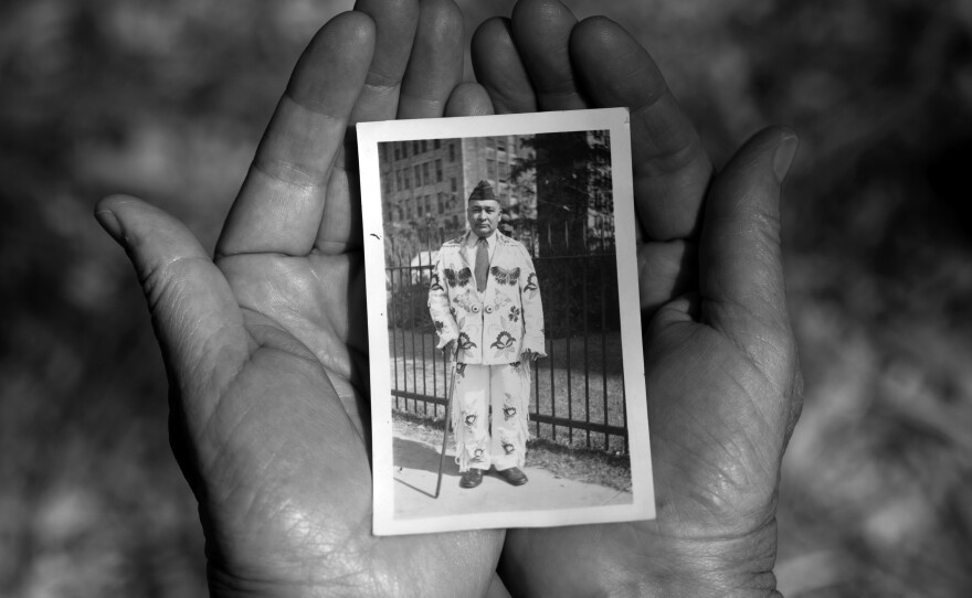 Sheridan MacKnight holds a photograph of her grandfather John B. McGillis. In the photograph, McGillis wears a hand-made beaded buckskin suit and a U.S. army cap from his service in WWI.