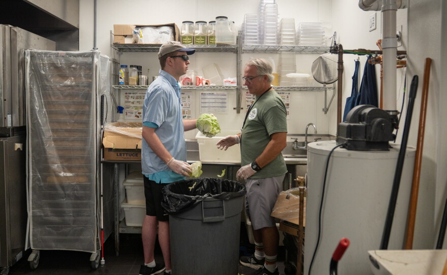 Cody bops lettuce at Jersey Mike's Subs with the help of his Next Steps job coach, Colin Sabia. This extraction of the lettuce core and removal of spoiled leaves is part of his job training.