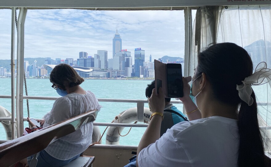 A passenger photographs Hong Kong's skyline while riding the Star Ferry.