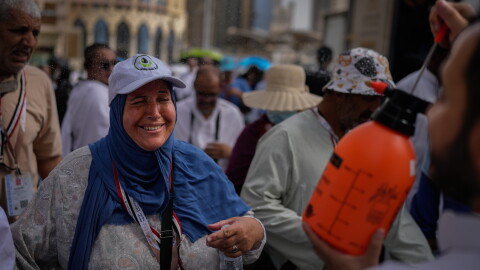 A Muslim pilgrim reacts as a volunteer sprays water to cool them outside the Grand Mosque during the annual hajj pilgrimage at the holy city of Mecca, Saudi Arabia, Sunday, May 24, 2026.