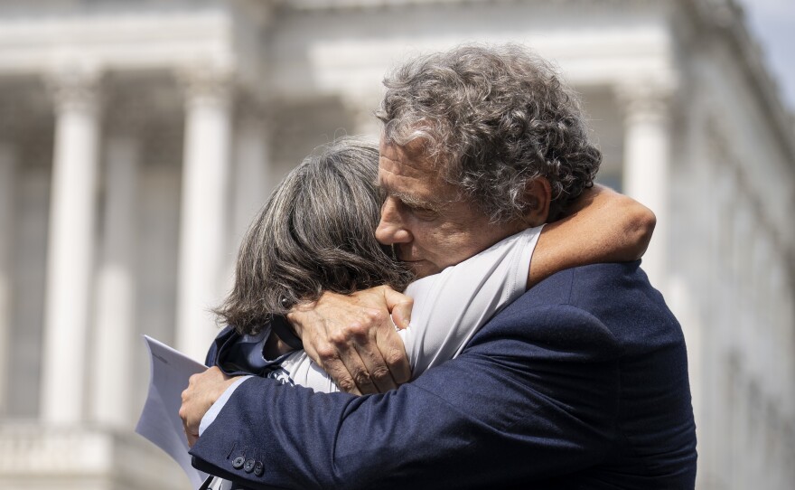 Susan Zeier, mother-in-law of the late Sgt. First Class Heath Robinson, hugs Sen. Sherrod Brown (D-Ohio) during Thursday's news conference.