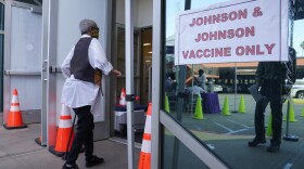 People walk in to get their COVID-19 vaccine at the Baldwin Hills Crenshaw Plaza past a sign that says "Johnson & Johnson vaccine only" in Los Angeles, April 1, 2021.