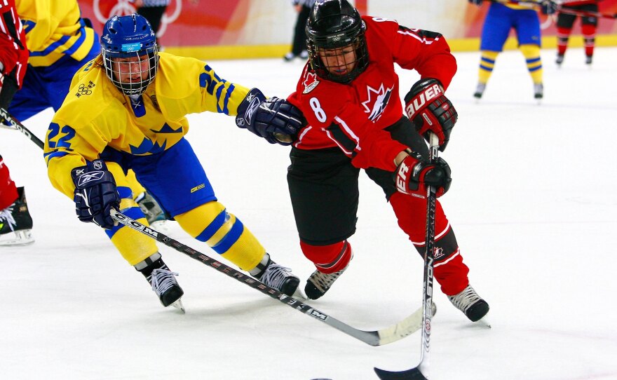 Katie Weatherston, right, fights for the puck against Sweden during the final game of the women's ice hockey tournament at the 2006 Winter Olympic Games in Turin, Italy.