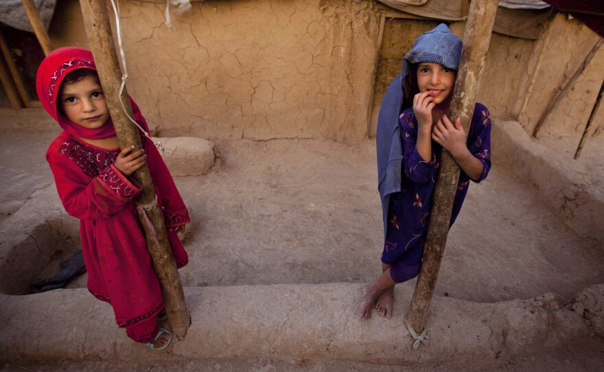 FILE: Zareena, left, and Shakeela, internally displaced Afghan girls play outside a shanty at a refugee camp in the outskirts of Kabul, Afghanistan, Monday, July 25, 2011.
