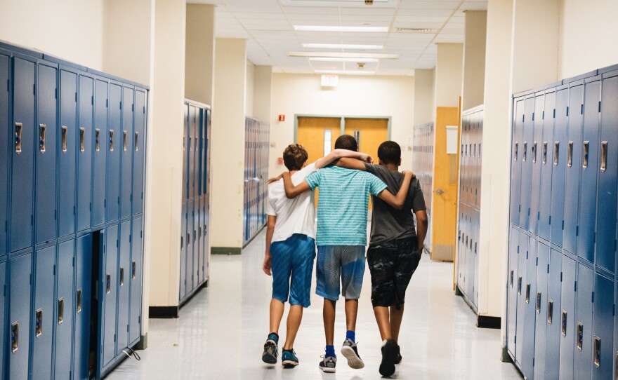 Bryan Bailey (right) and friends walk down the hallway arm in arm.