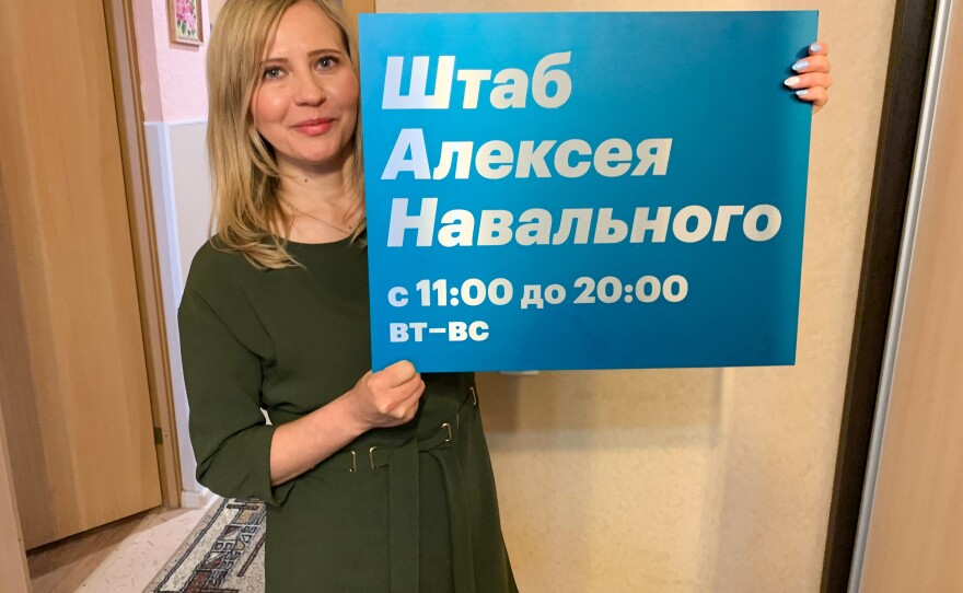 Yelena Agayeva holds up the sign of Alexei Navalny's Tula campaign headquarters, which her son, Filipp Simpkins, helped run. He has fled Russia and now has political asylum in Switzerland.