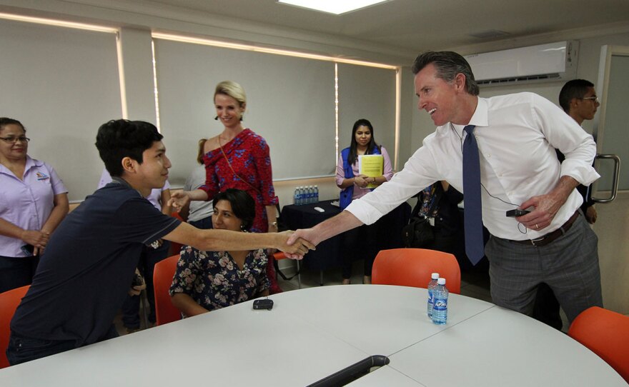 California Gov. Gavin Newsom, right, and his wife, Jennifer Siebel Newsom greet Byron Daniel, 17, a young Salvadoran, who had fled El Salvador due to the harassment of gang members looking to recruit him, during their visit to La Chacra Immigration Center in San Salvador, El Salvador, Monday, April 8, 2019. The Migrant Care Center processes deported migrants.