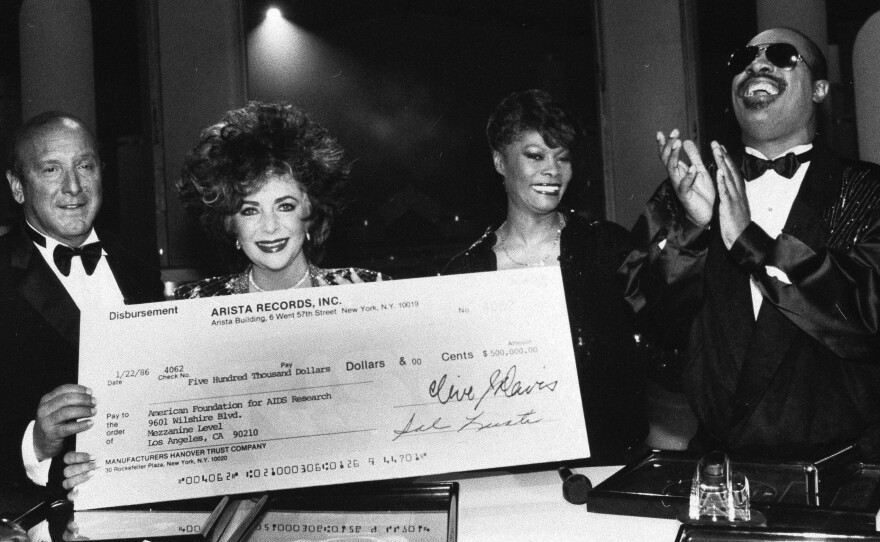 Clive Davis displays a $500,000 check with Elizabeth Taylor, Dionne Warwick and Stevie Wonder at a charity event in Holywood in 1986.