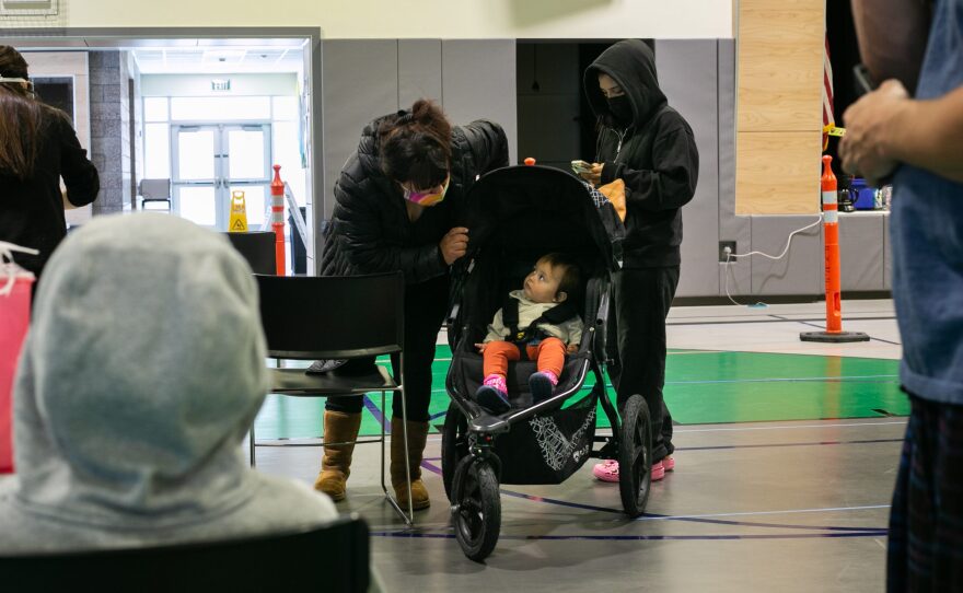 Monica Aiken checks on Alaska Dey while they wait to get their COVID-19 booster shot and flu shots at La Mirada Academy in San Marcos, Calif. in this undated photo.