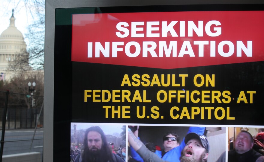 An information board shows people who are wanted by law enforcement on suspicion of assaulting federal officers at the U.S. Capitol during the Jan. 6 riot.