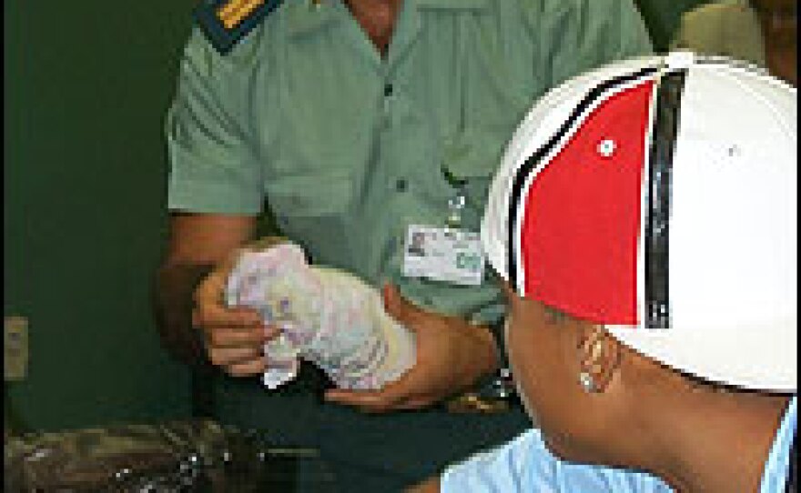 Police at the airport inspect a suitcase. In the past, they have confiscated cocaine in a variety of containers: suitcases with secret compartments, wheelchairs, bowling balls and tropical fruit.