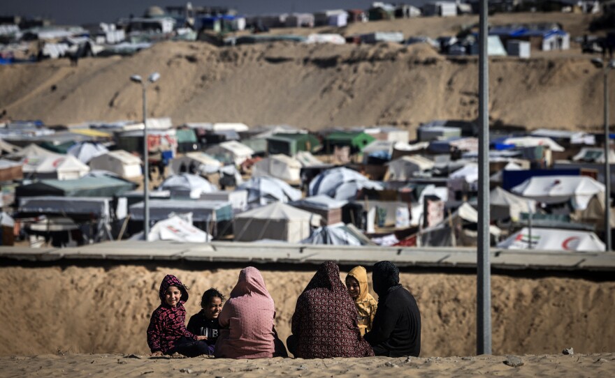 Displaced Palestinian women and children gather on a sand dune above a makeshift camp on the border with Egypt, west of Rafah in the southern Gaza Strip, on Jan. 14.