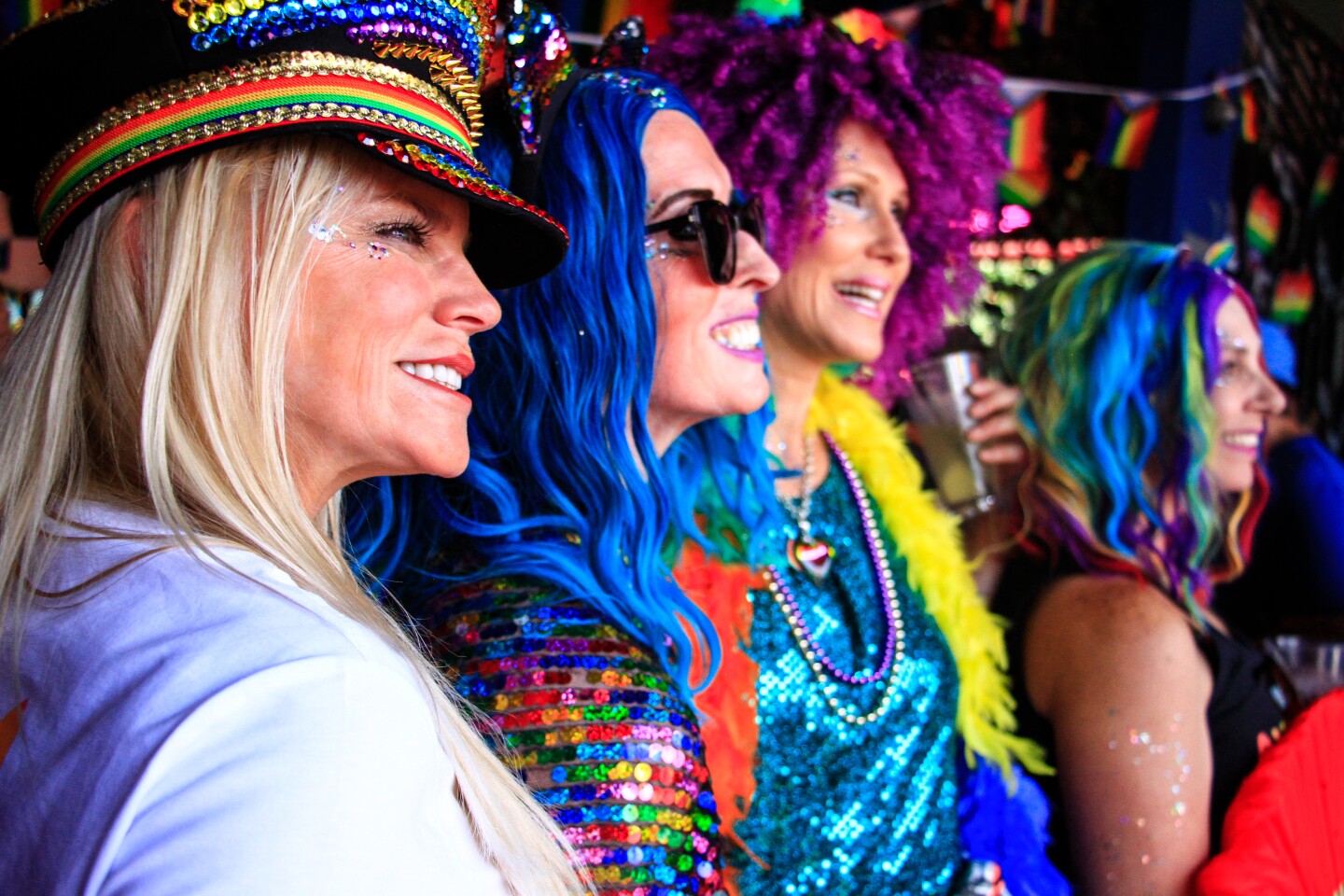 Pride parade attendees dressed in rainbow colors and wigs pose for a photo, July 15, 2023.