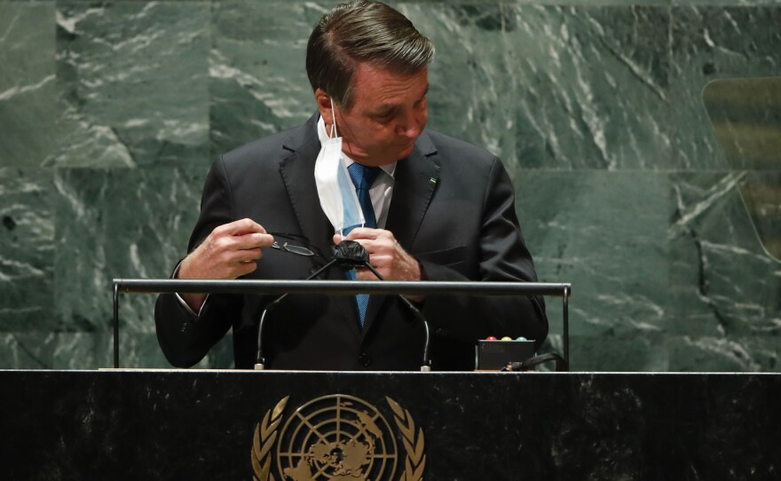 Brazil's President Jair Bolsonaro pulls off his protective face mask to address the 76th Session of the U.N. General Assembly at United Nations headquarters in New York, Tuesday, Sept. 21, 2021.