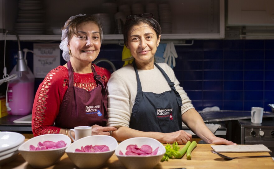 Two Syrian refugees, Narwal Alakayleh (left) and Lina AlAlssantin (right), prepare for a pop-up dinner of Levantine food at Newcomer Kitchen.