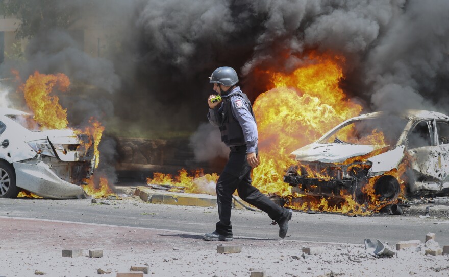 An Israeli firefighter walks next to cars hit by a rocket fired from the Gaza Strip, in the southern Israeli city of Ashkelon on Tuesday.
