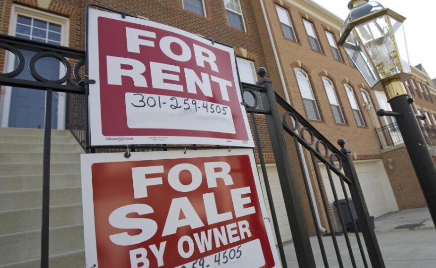 "For Sale" and "For Rent" signs are seen on the front of townhomes in Centreville, Va.