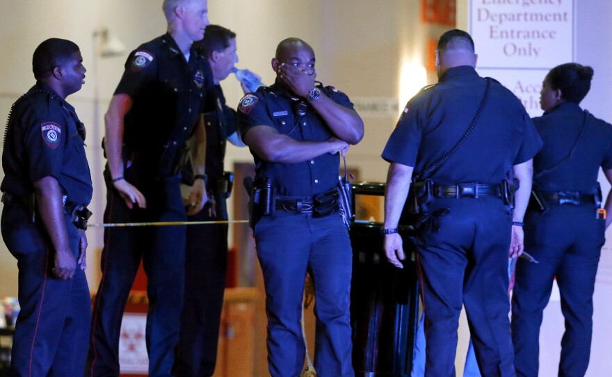 A Dallas police officer covers his face as he stands with others outside the emergency room at Baylor University Medical Center in Dallas. Snipers opened fire on police officers Thursday night, killing some of the officers.