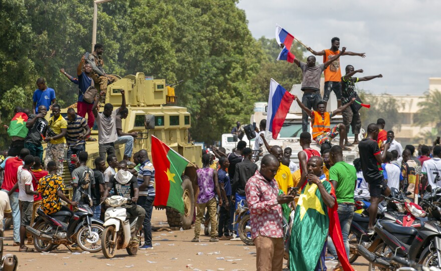 Supporters of Capt. Ibrahim Traore cheer with Russian flags in the streets of Ouagadougou, Burkina Faso, on Sunday. Burkina Faso's new junta leadership is calling for calm after the French Embassy and other buildings were attacked.