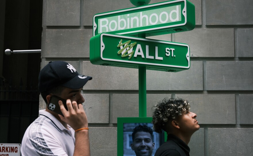 People wait in line for T-shirts at a pop-up kiosk for the online brokerage Robinhood along Wall Street in New York City on July 29, the day the company listed in stock markets. Millions of amateur investors are buying stocks through apps such as Robinhood.