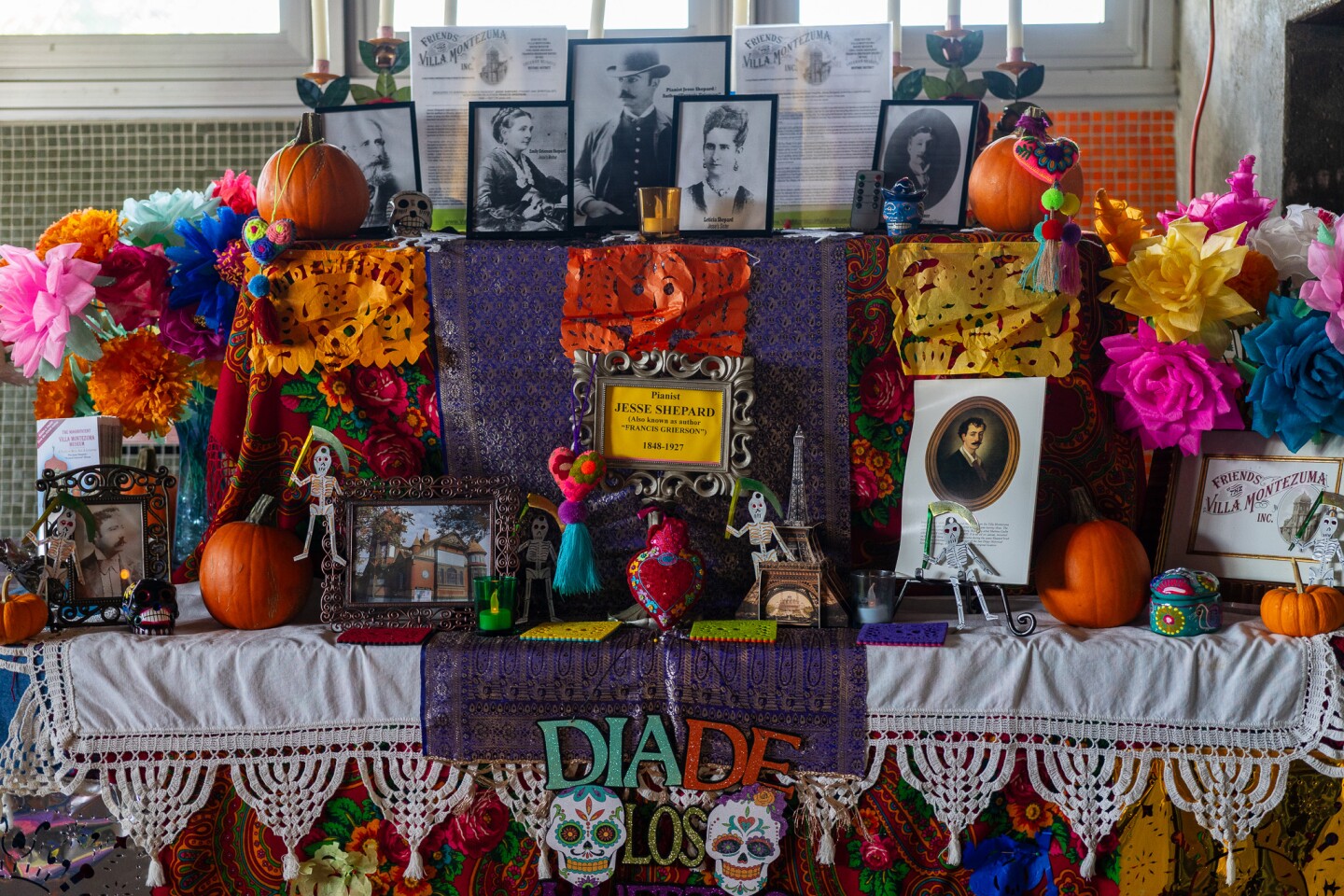An altar created by the Friends of Villa Montezuma at the Sherman Heights Community Center in San Diego is decorated with pictures of loved ones, papel picado, pumpkins and decorated skeletons on Oct. 17, 2023.