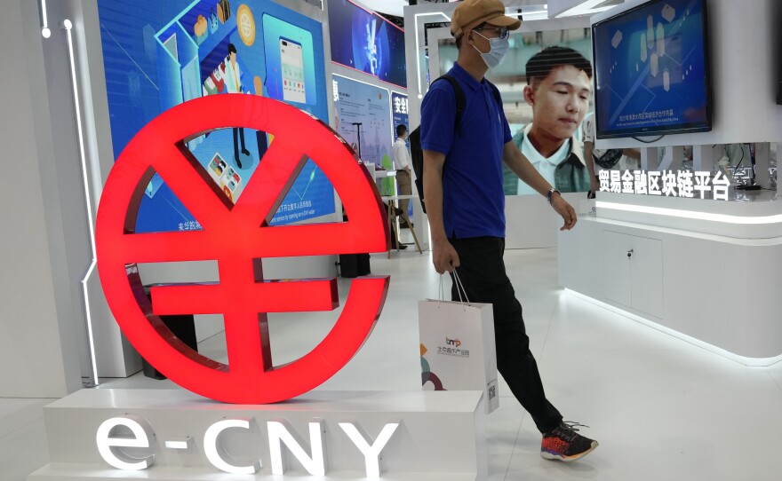 A visitor passes by a logo for the e-CNY, a digital version of the Chinese yuan, displayed during a trade fair in Beijing, last September. That same month, China's central bank declared all transactions involving Bitcoin and other virtual currencies illegal, stepping up a campaign to block use of unofficial digital money.