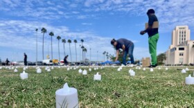 People set up flameless tea lights in San Diego's Waterfront Park on Oct. 10, 2025, preparing for a vigil to honor homeless San Diegans who have died.