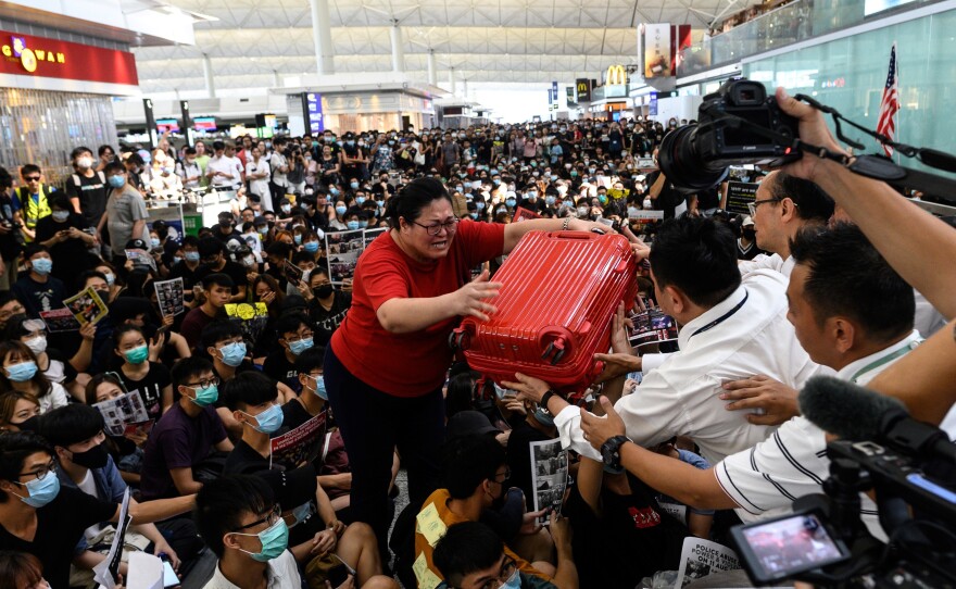 A tourist gives her luggage to security guards as she tries to enter the departures gate during another demonstration by pro-democracy protesters at Hong Kong's international airport on Tuesday.