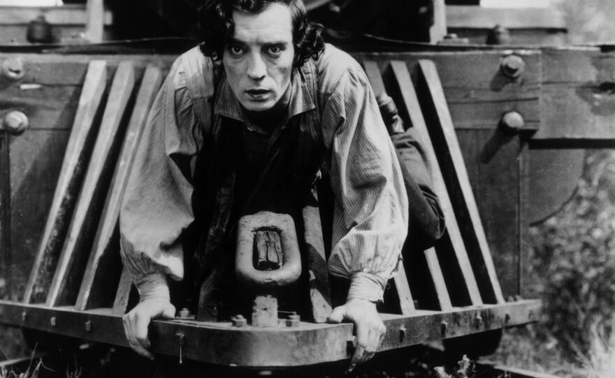 American actor Buster Keaton clinging to the front of a train in a still from the 1926 film, 'The General.'