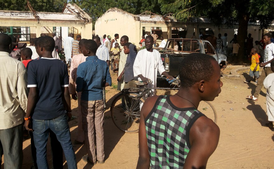 People inspect the site of a suicide bomb explosion at the Government Science Technical College in Potiskum, Nigeria, Monday. Survivors say a bomber disguised in a school uniform detonated explosives during an assembly at the school.