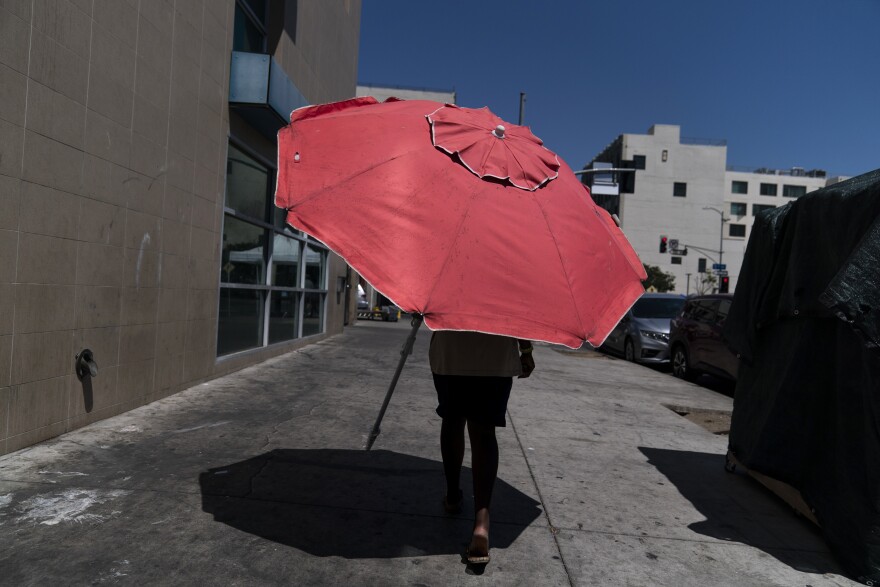 A woman walks with a beach umbrella in Los Angeles, Wednesday, Aug. 31, 2022. Excessive-heat warnings expanded to all of Southern California and northward into the Central Valley on Wednesday, and were predicted to spread into Northern California later in the week. 