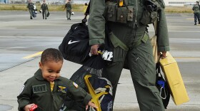 Lt. Cmdr. Chris Singletary, assigned to the Chargers of Helicopter Anti-Submarine Squadron (HS) 14, walks with his son on the flight line during a homecoming celebration. HS-14 completed a deployment aboard the aircraft carrier USS George Washington (CVN 73). 