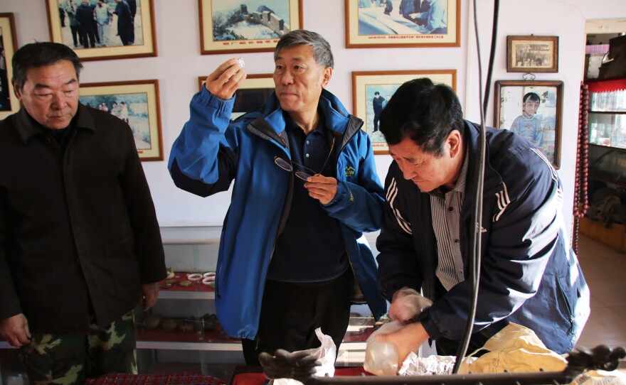 China Great Wall Society vice chairman Dong Yaohui (center) examines artifacts from the Great Wall with Xu Guohua (right), who opened a museum for these objects.