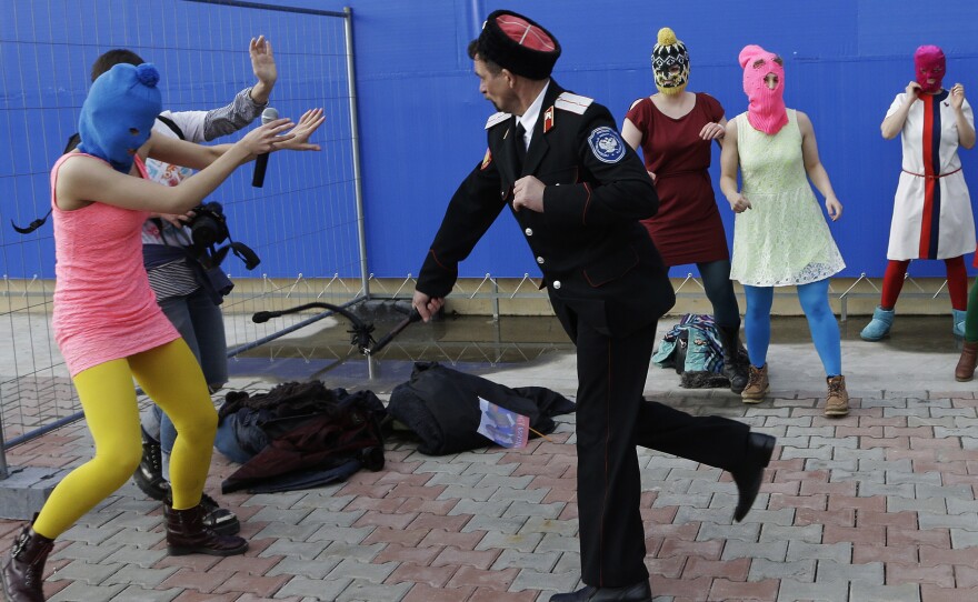 A Cossack militiaman attacks Nadezhda Tolokonnikova and a photographer as she and fellow members of the punk band Pussy Riot, including Maria Alyokhina, center, in the pink balaclava, stage a protest performance in Sochi on Wednesday.