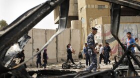 Iraqis inspect the site of a car bomb attack Sunday near the Iranian Embassy in Baghdad.