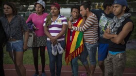 In this Nov. 4, 2018 photo, members of a group of 50 or so LGBTQ migrants, stand on the race track at the Jesus Martinez stadium that was turned into a makeshift shelter, in Mexico City.