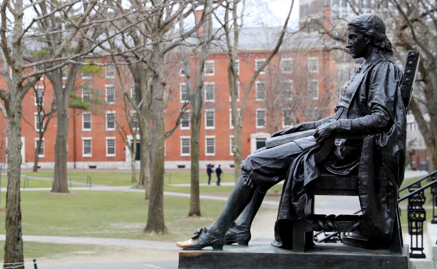 A statue of John Harvard, namesake of the university, overlooks the campus earlier this year. Harvard University joined the Massachusetts Institute of Technology in suing the federal government over its policies on international students Wednesday.