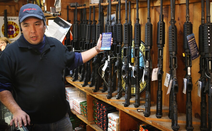 At the Freddie Bear Sports shop in Tinley Park, Ill., Jason Zielinski shows AR-15 style rifles to a customer.