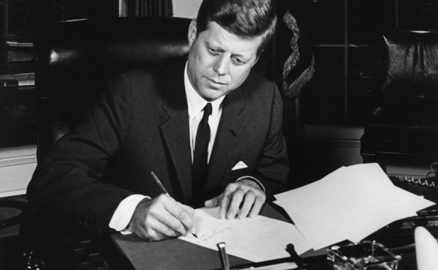 President Kennedy signs the Interdiction of the Delivery of Offensive Weapons to Cuba Proclamation, October 23, 1962, at the White House.