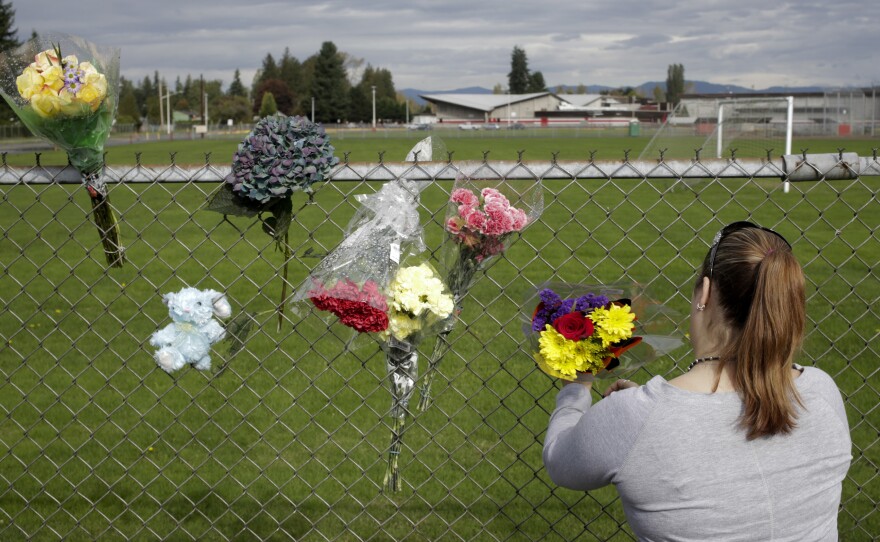 A visitor leaves flowers on Saturday, the day after a shooting at Marysville-Pilchuck High School in Marysville, Wash.