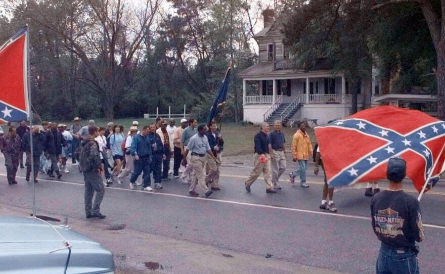 The "Get In Step" marchers pass by a small group of Confederate Flag supporters Tuesday, April 4, 2000, near Wells, S.C., on their way to Orangeburg on the third day of the march to Columbia to have the flag taken down from the Statehouse.