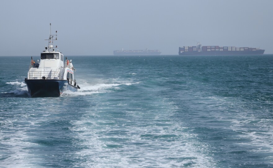 A patrol boat moves through the water as cargo ships sit at anchor in the Strait of Hormuz off Bandar Abbas, Iran, Saturday.