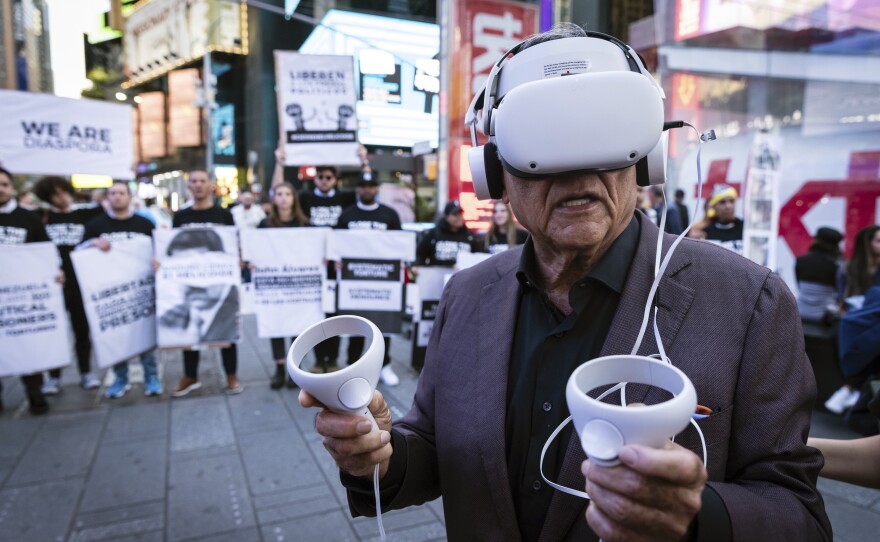 A person standing near Times Square in New York City wears a virtual reality headset screening an immersive experience of the conditions at Venezuela's El Helicoide prison, on Sept. 19, 2023. Protesters gathered to demand the release of political prisoners and the closure of the detention center over allegations of torture.